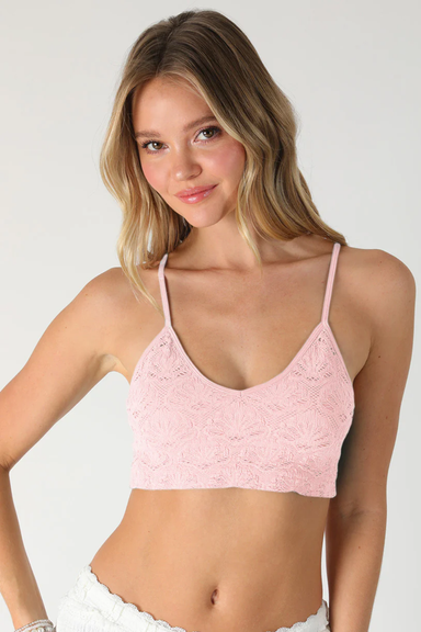 Woman wearing a pink lace bralette against a plain background