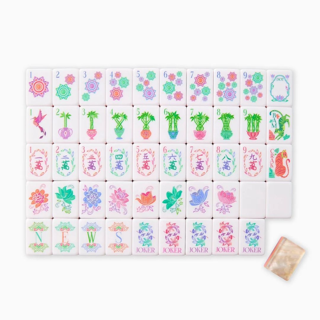 Full mahjong tile set arranged in rows on a white background, featuring colorful floral dot, bamboo, character, flower, wind and joker designs in pink, green, purple and orange, with one tile placed separately beside the set.