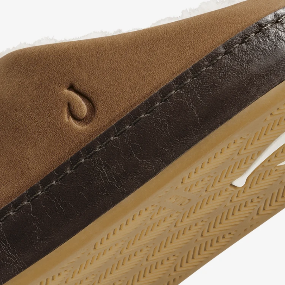 Close-up detail of a brown suede shoe upper with a dark brown leather stripe, contrast stitching, and a tan textured outsole.