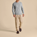 Man wearing a gray sweater and beige pants on a beige background