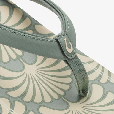 Close-up of a sandal with floral pattern and green strap on a light gray background