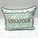 A rectangular decorative throw pillow with a cream background, teal oyster shell pattern, and black piping. The center features a black scalloped border with the word 'ANNAPOLIS' printed in black serif letters.