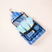 A blue patterned mesh travel toiletry bag with black zipper and trim, shown open and filled with matching blue toiletry items on a plain light beige background.