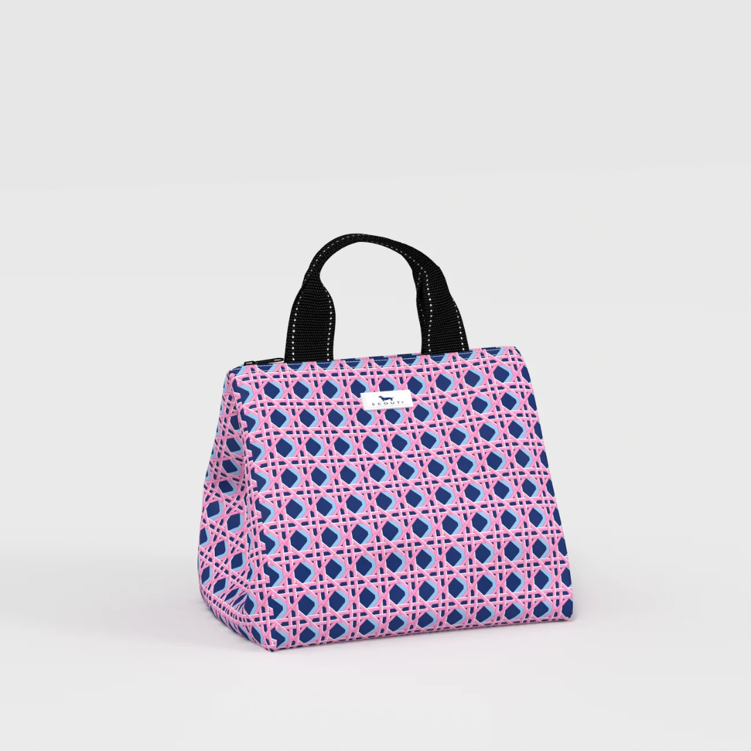 A structured canvas lunch bag with a pink and blue geometric trellis pattern and black top handles, shown on a light gray studio background.