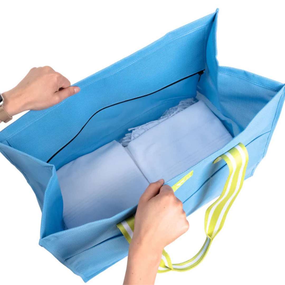 Blue storage bag with handles being held open by hands on a white background
