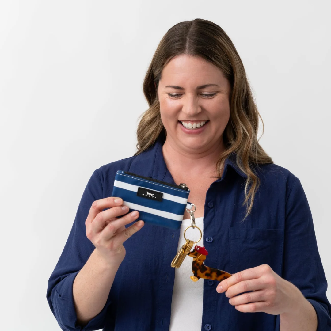 Woman holding a striped pouch and keychain with a white background