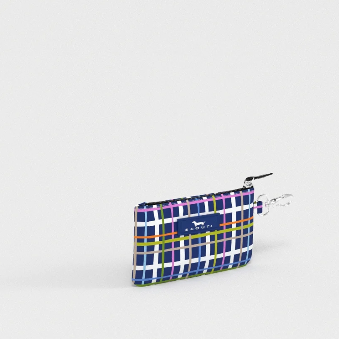 A small zippered pouch with a colorful plaid pattern in blue, purple, green, and white, featuring a blue brand label that reads 'KAVU' and a silver metal clip attachment.