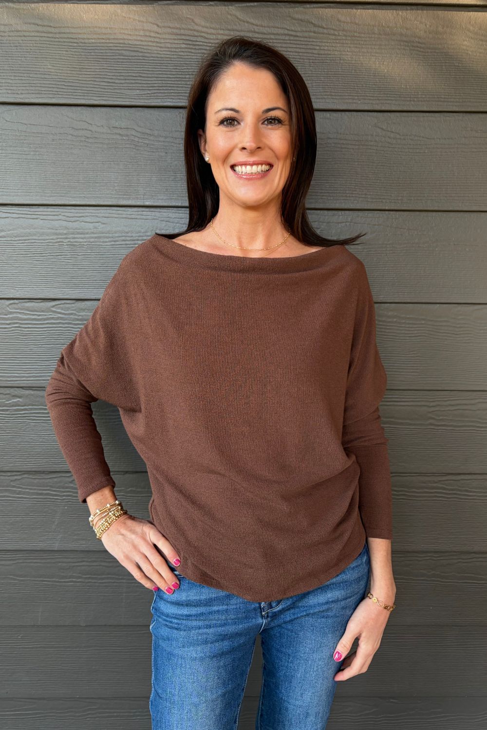 Woman wearing Six Fifty Anywhere Top In Chestnut with jeans on a dark wood background.