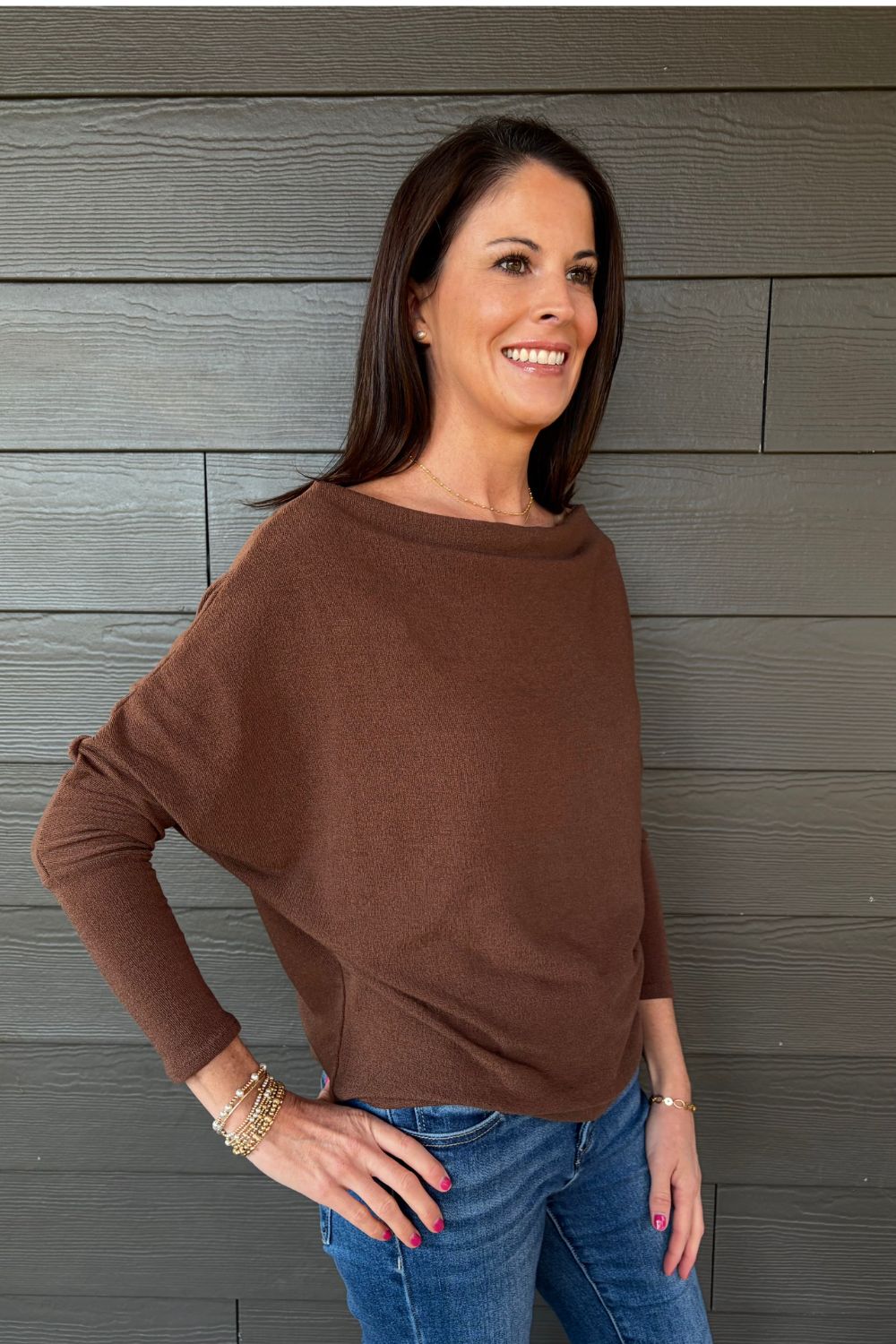 Woman wearing Six Fifty Anywhere Top In Chestnut with jeans on a dark wood background.