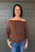 Woman wearing Six Fifty Anywhere Top In Chestnut with jeans on a dark wood background.