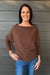 Woman wearing Six Fifty Anywhere Top In Chestnut with jeans on a dark wood background.