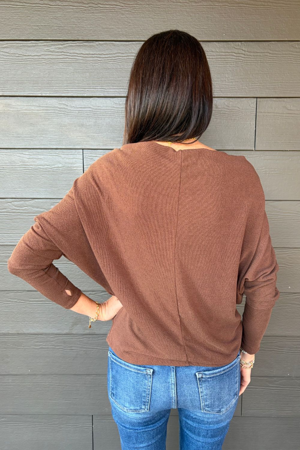 Woman wearing Six Fifty Anywhere Top In Chestnut with jeans on a dark wood background.