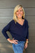 A woman wearing Six Fifty Anywhere Top In Navy with jeans on a dark wood background.