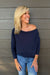 A woman wearing Six Fifty Anywhere Top In Navy with jeans on a dark wood background.