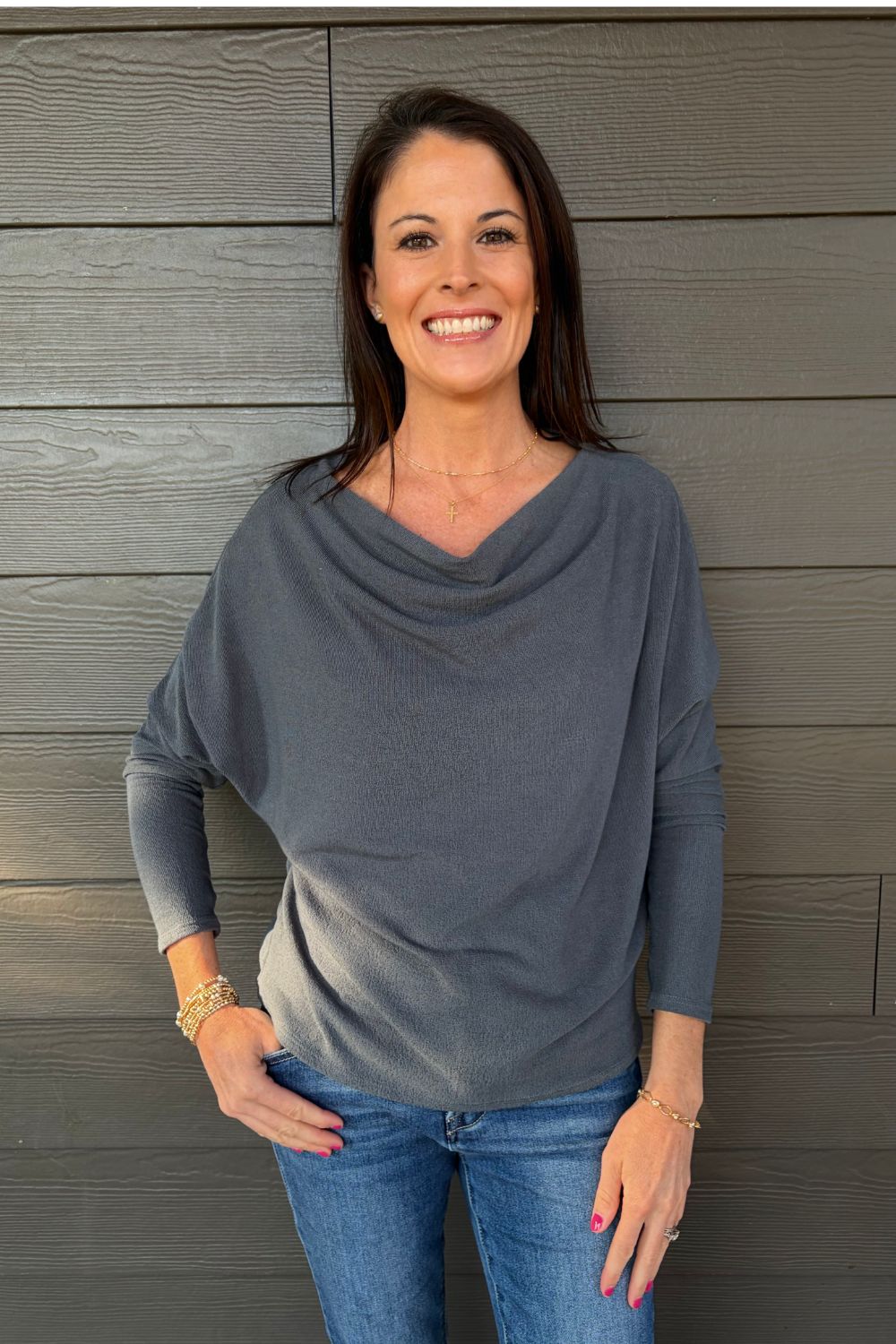 Woman wearing Six Fifty Anywhere Top In Slate with blue jeans on a dark wood background.