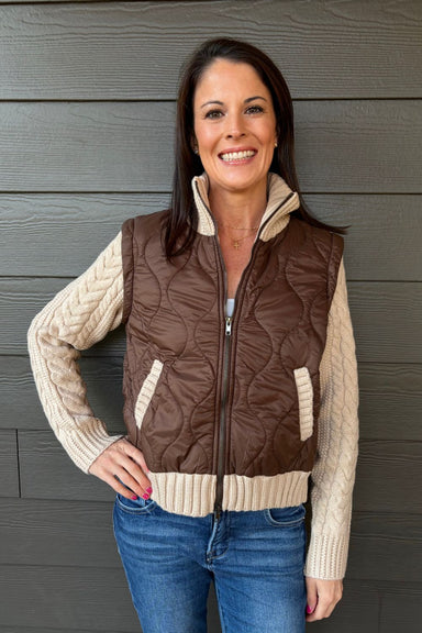 Woman wearing Six Fifty Melanie Mixed Media Jacket In Brown with jeans on a dark wood background.