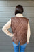 Woman wearing Six Fifty Melanie Mixed Media Jacket In Brown with jeans on a dark wood background.