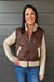 Woman wearing Six Fifty Melanie Mixed Media Jacket In Brown with jeans on a dark wood background.