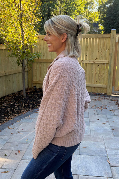Woman wearing Softies Cable Knit Marshmallow Funnel Neck Double Zip Jacket Coco with blue jeans on standing on a patio.