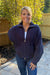 Woman wearing Softies Cable Knit Marshmallow Funnel Neck Double Zip Jacket Midnight with blue jeans on a patio that is fenced in.
