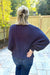 Woman wearing Softies Cable Knit Marshmallow Funnel Neck Double Zip Jacket Midnight with blue jeans on a patio that is fenced in.