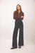 A woman modeling a dark brown long-sleeve zip-up sweater and black wide-leg pants against a plain light gray studio background.