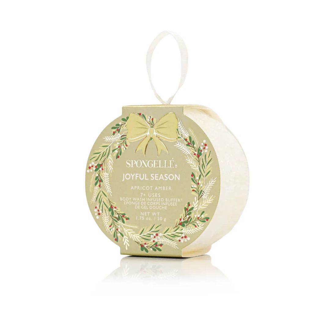 SpongeLLe Joyful Season Apricot Amber body wash in a round hanging box with a pale green label, white sponge inside, and a white hanging loop on a white background.