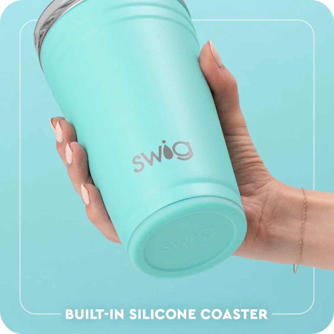 Hand holding a turquoise Swig tumbler with a built-in silicone coaster on a light blue background.
