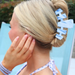 Person with a bun wearing a blue hair clip with letters, sitting on a blue chair.