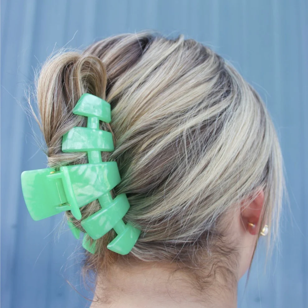 green hair clip in models hair against neutral background