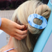 Person styling hair with a blue and white hair clip outdoors