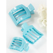 Three light blue hair clips on a white background with a touch of white flowers.