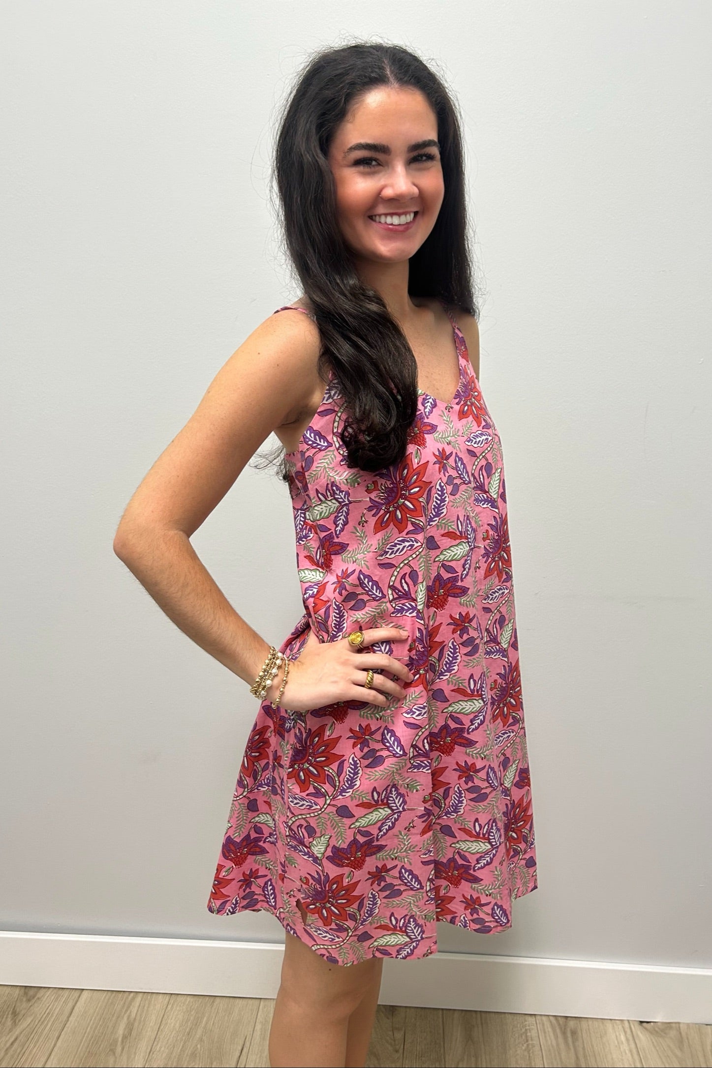 Woman wearing pink dress with colorful flowers against gray background