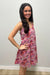 Woman wearing pink dress with colorful flowers against gray background