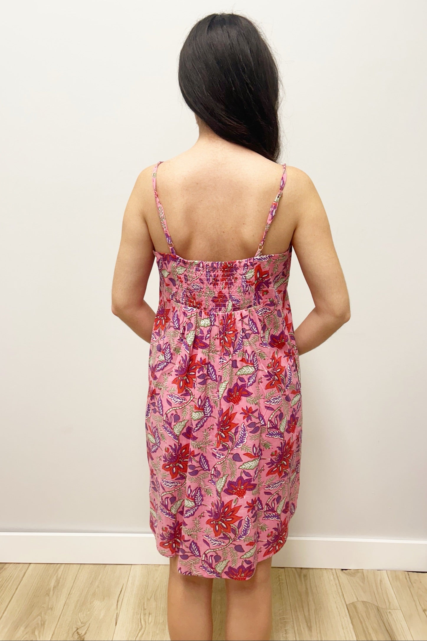 Woman wearing pink dress with colorful flowers against gray background