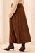 A brown pleated midi skirt worn with a cream sweater and dark brown pointed-toe ankle boots, shown from the waist down in a softly lit indoor setting.