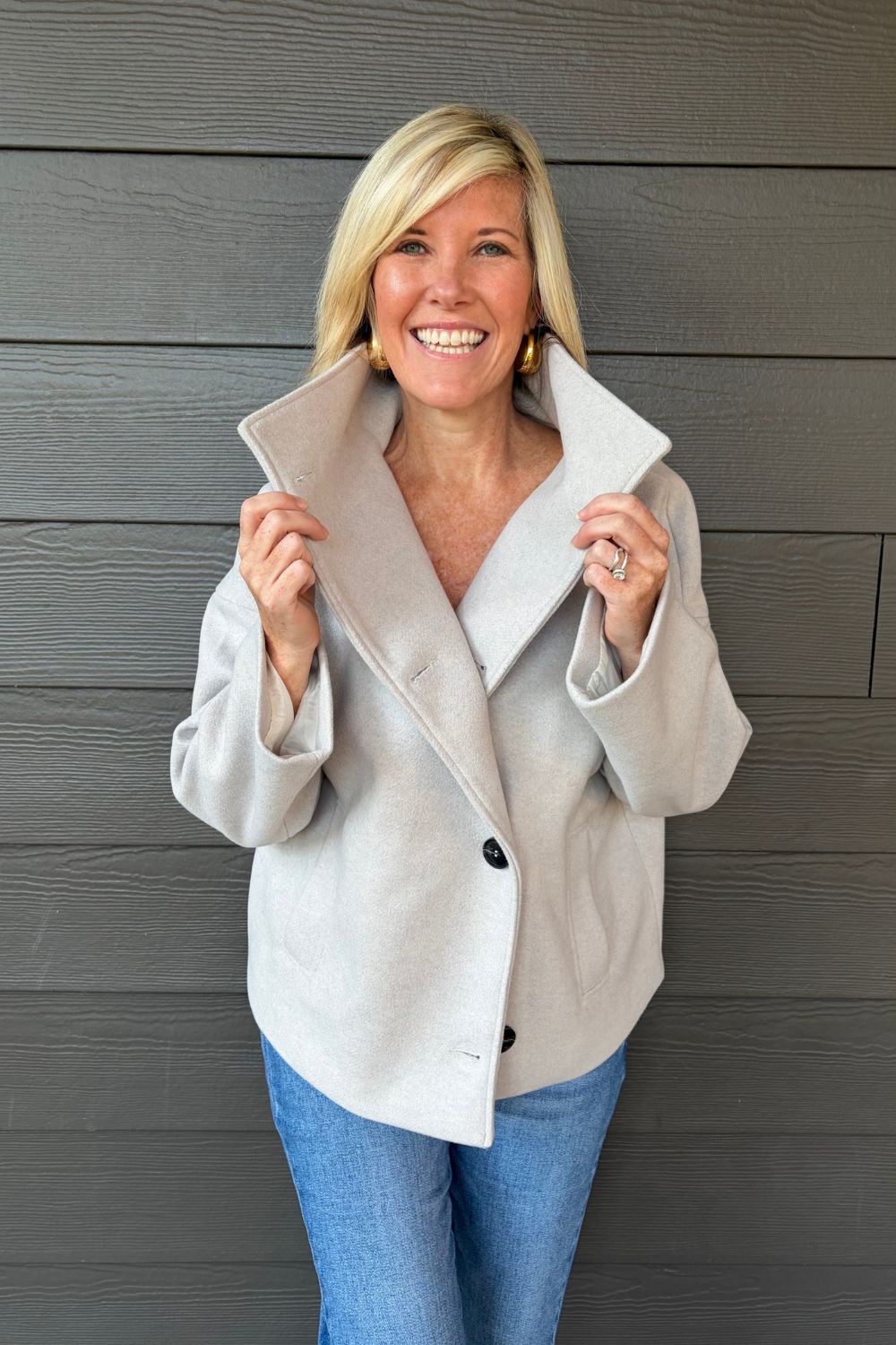 Woman wearing Tribal Sportswear Lofty Chic Funnel Neck Jacket In Antique White with jeans on a dark wood background.