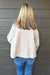 Woman wearing Tribal Sportswear Lofty Chic Funnel Neck Jacket In Antique White with jeans on a dark wood background.