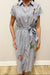 Person wearing a dress with colorful embroidery against a plain background