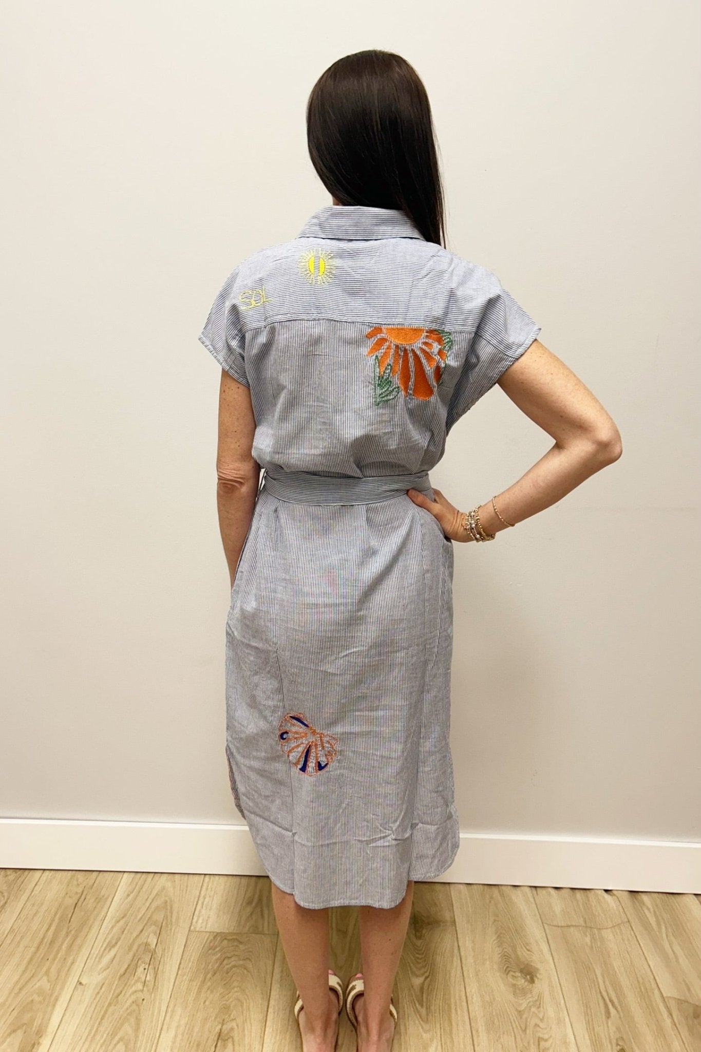Woman wearing a dress with colorful floral patterns on a plain background