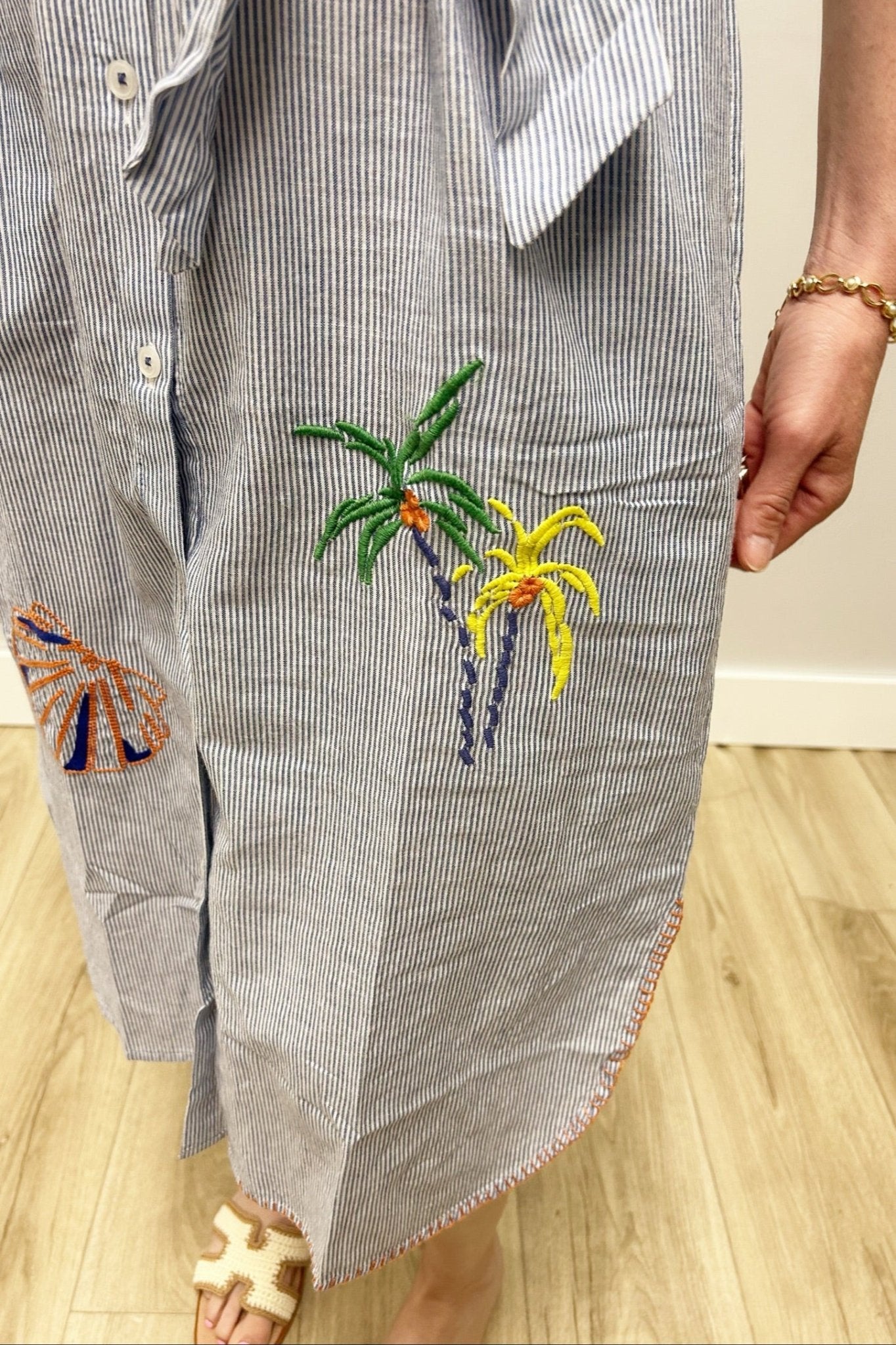 dress with embroidered palm trees on a wooden floor.