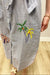 dress with embroidered palm trees on a wooden floor.