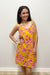 Woman wearing a mustard yellow dress with pink pattern