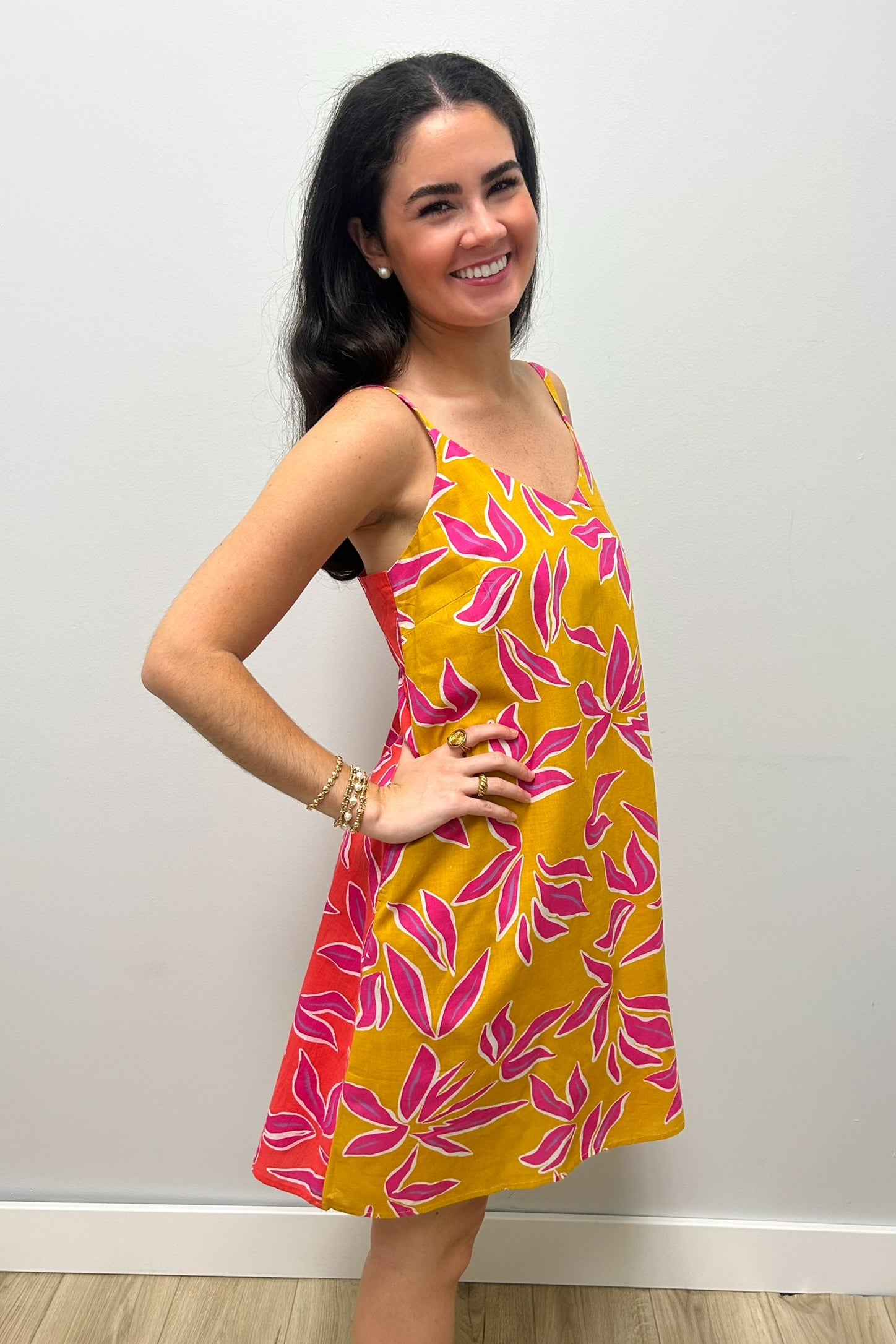Woman wearing a mustard yellow dress with pink pattern
