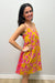 Woman wearing a mustard yellow dress with pink pattern