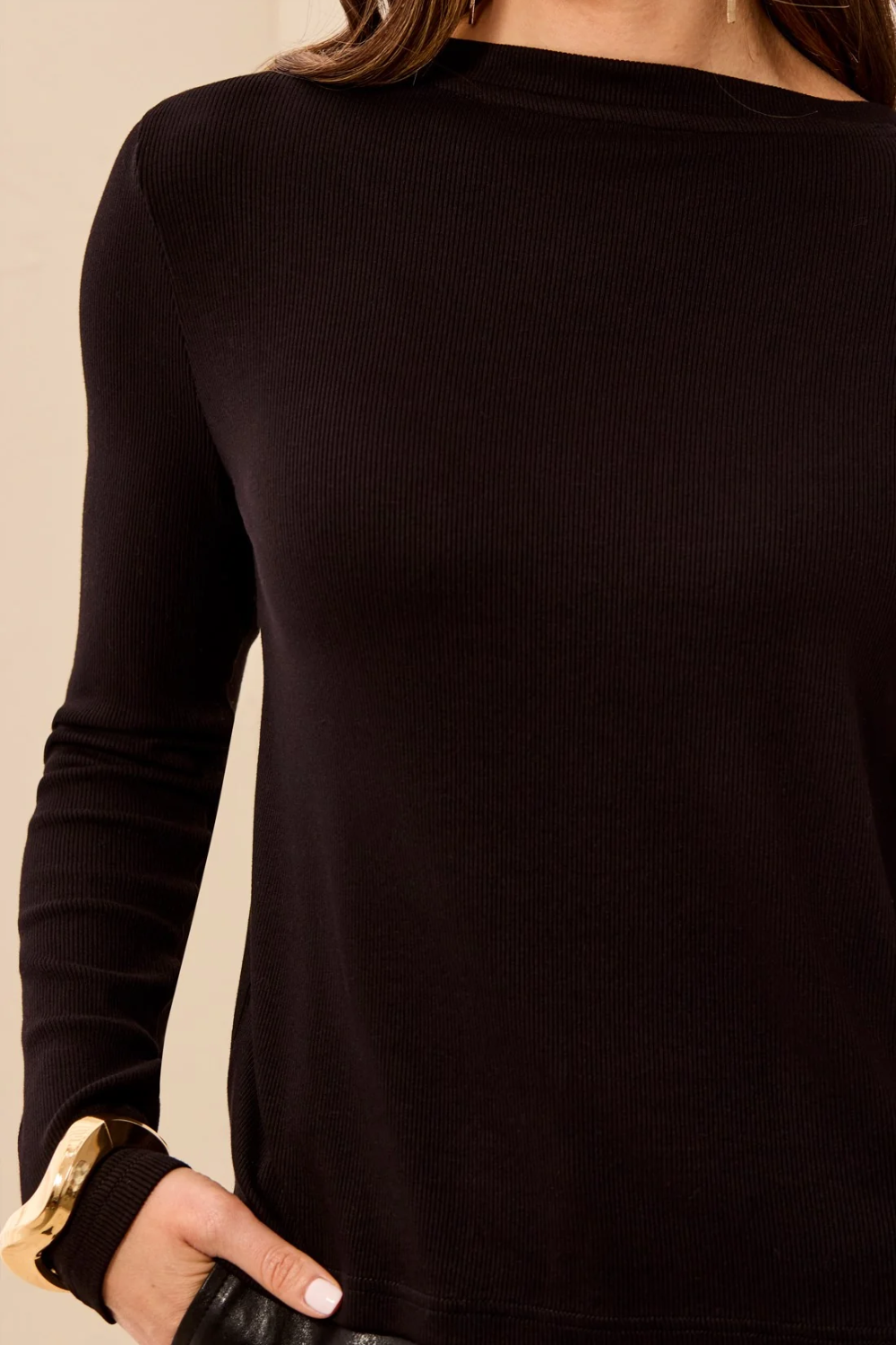 A close-up of a woman wearing a dark brown ribbed knit long-sleeve top, showing the texture and fit against a neutral beige background.