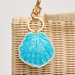 Blue shell keychain on a wicker bag with a light background