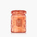 A Voluspa Spiced Pumpkin Latte scented candle in a textured, translucent orange glass jar with a matching lid, set against a clean white background.