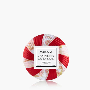 A round coconut wax candle with a red and white striped candy cane design and a white label in the center that reads 'VOLUSPA CRUSHED CANDY CANE COCONUT WAX CANDLE'.
