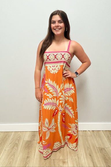 woman wearing orange dress with pink detailing on plain background